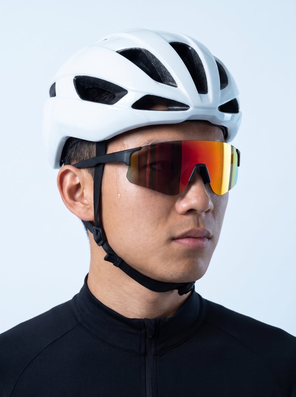 Cycliste sur route en casque aéro blanc portant Shield 01 en Onyx avec un verre Blaze